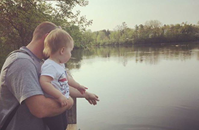 man with child near river and trees